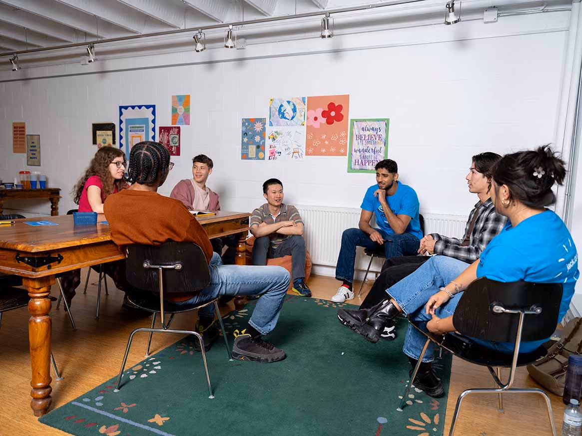 Students discussing and sitting around tables in a workshop