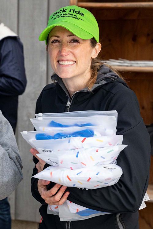 Participant holding jack ride t-shirts or jerseys wearing a green hat and smiling