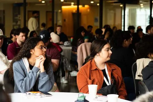 Participants at a conference watching a speaker off screen