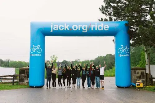 Group of jack ride participants standing under jack.org banner outdoors