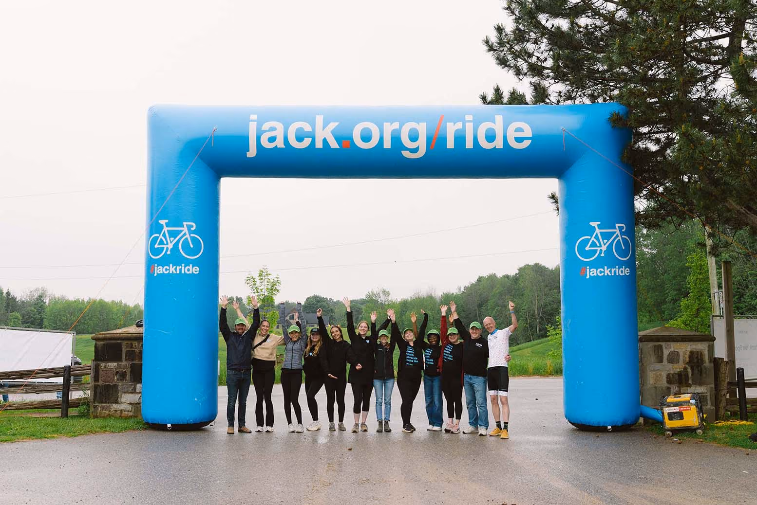 Group of jack ride participants standing under jack.org banner outdoors