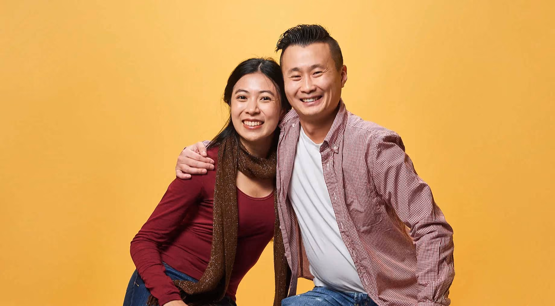 two bethere people in front of a yellow background hugging 