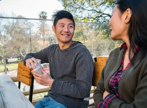 two people chatting on an outdoor table while drinking coffee