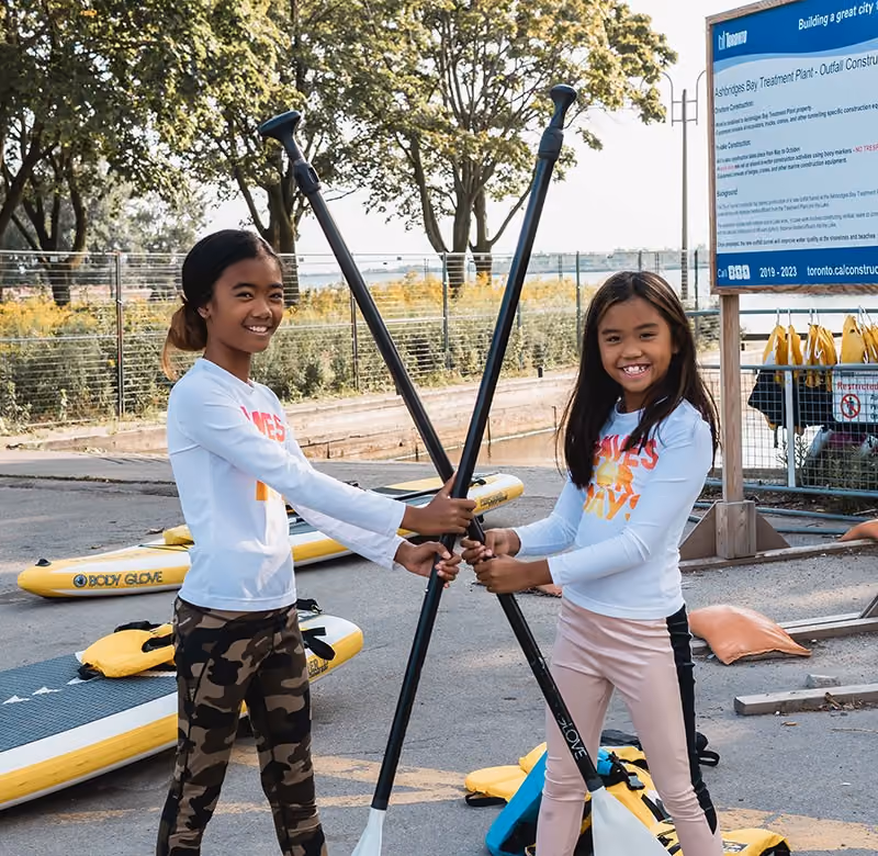Two youth with paddles in front of lake side