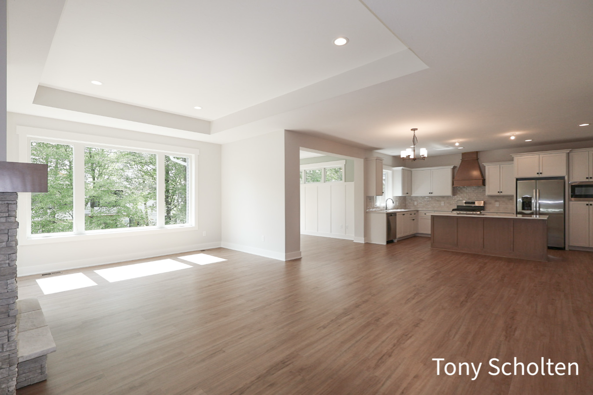 Spacious open living area with large window, hardwood floors, and a modern kitchen with island and stainless steel appliances.