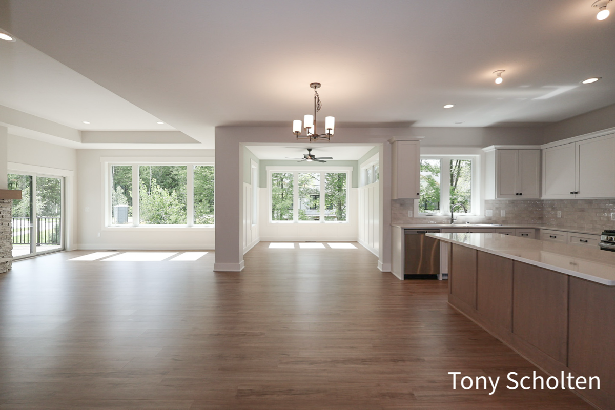 Open floor plan with large windows, modern kitchen with island, and wood flooring.