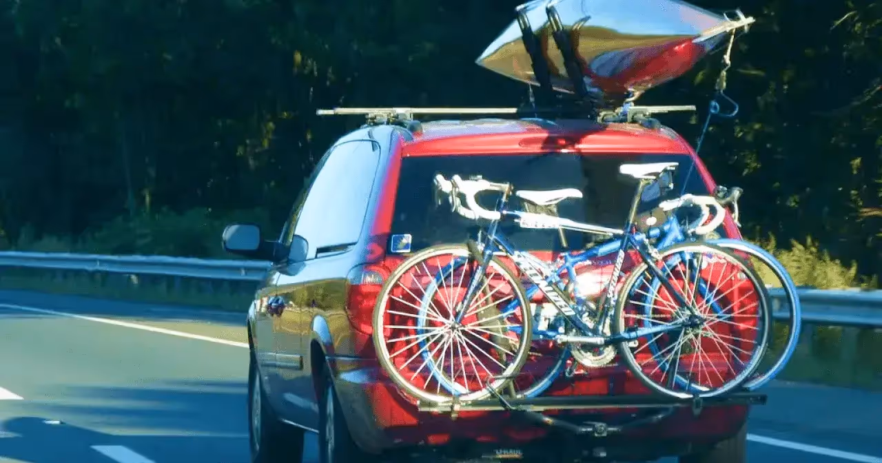 red suv transporting road bikes and kayak