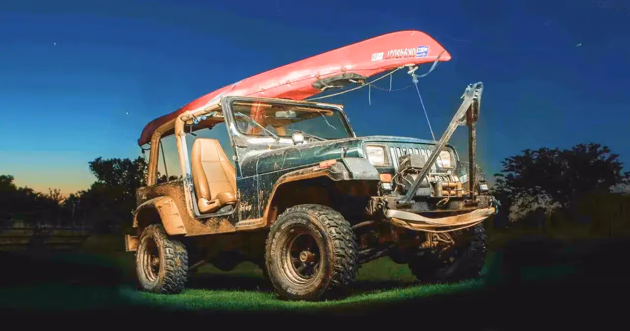 jeep with kayak mounted on the roof rack at night