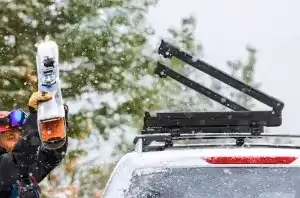 person attaching skis to vehicle magnetic roof rack