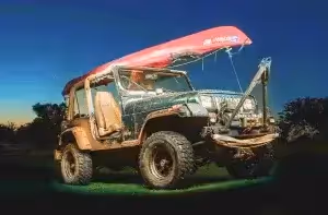jeep with kayak mounted on the roof rack at night