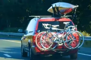 red suv transporting road bikes and kayak