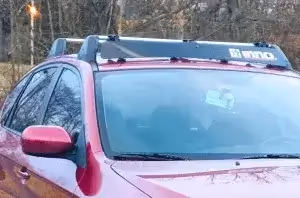 red vehicle with roof rack and wind noise guard