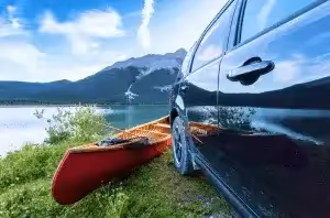canoe next to vehicle and mountain lake