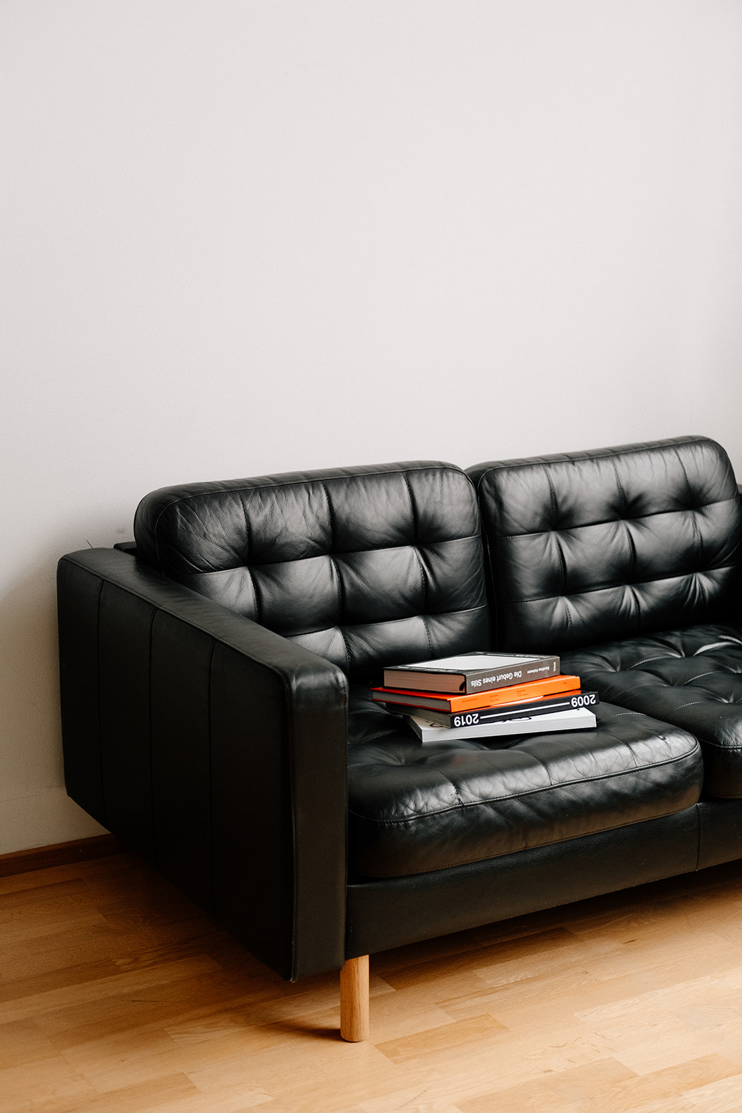 Ein Ledersofa. Auf dem Sofa liegen Bücher aufeinander gestapelt.