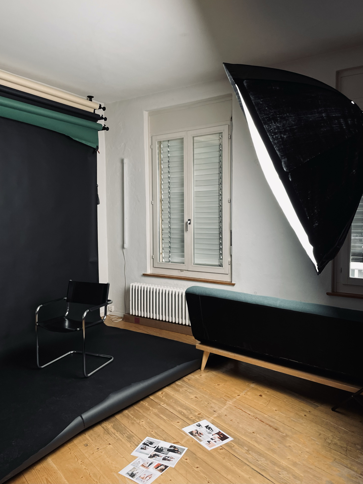 Fotografiestudio. Ein Stuhl steht vor einer dunklen Leinwand. Rechts befindet sich ein grosses Licht.