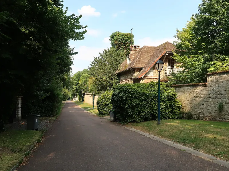 Allée arborée longée par une maison à toit de tuiles à Rueil-Malmaison