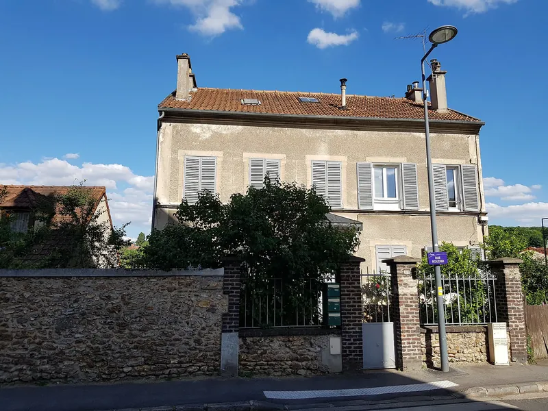 Maison de ville à volets gris derrière un mur de meulière à Meudon