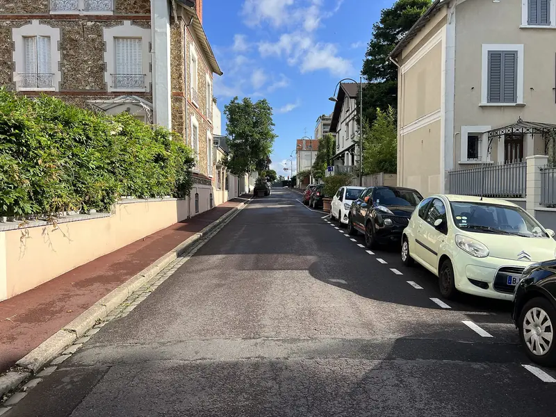 Rue en pente bordée de maisons et de haies à Sceaux