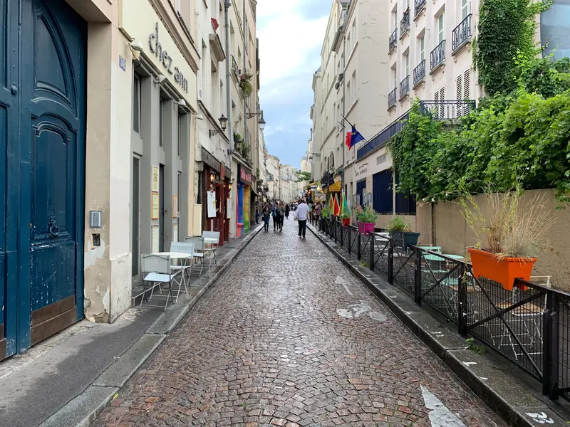 Rue Mouffetard pavée, entre portes cochères et terrasses, dans le 5e