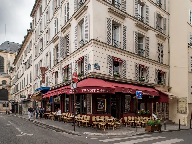 Immeuble d'angle à volets et café à auvent rouge, rue Guisarde, dans le 6e