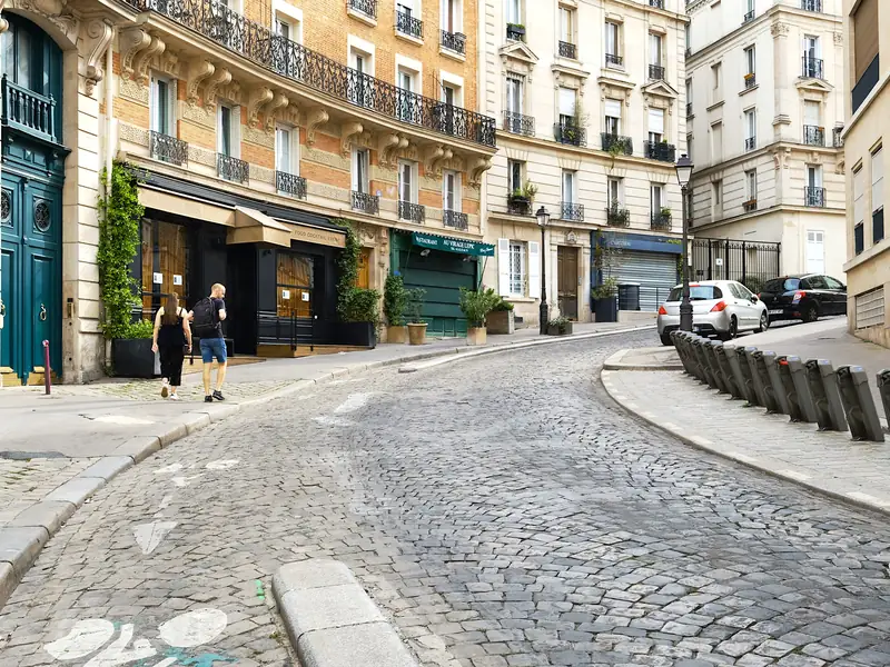 Rue Lepic pavée et en courbe, bordée d'immeubles en pierre, dans le 18e