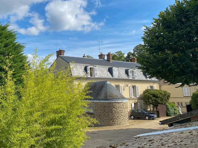 Grande maison à toit d'ardoise entre les arbres à Évry-Courcouronnes