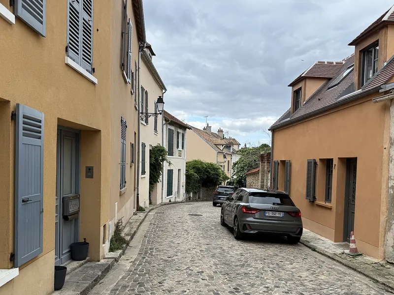Rue pavée bordée de maisons de village à volets à Marly-le-Roi