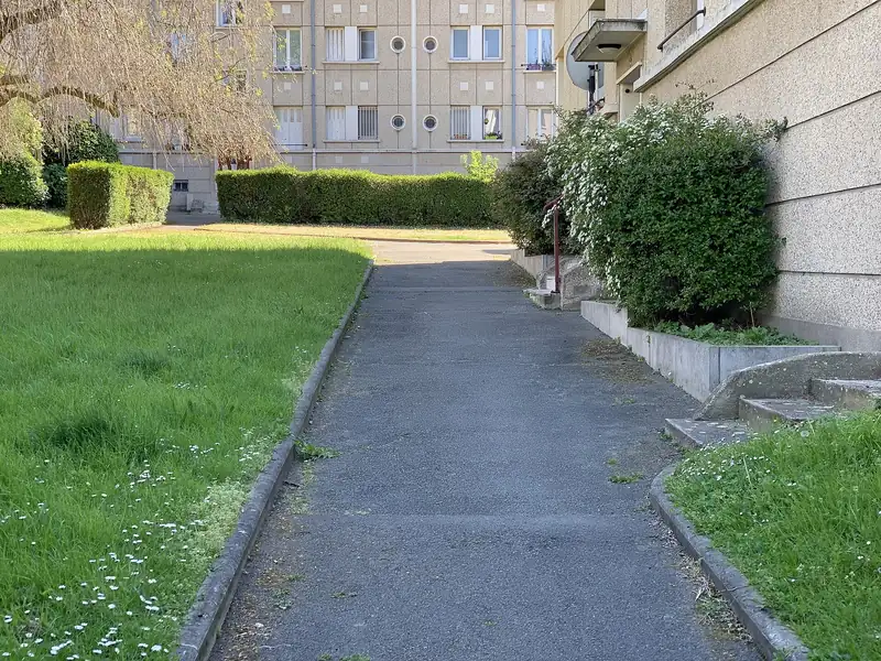Allée piétonne entre une pelouse et des immeubles d'habitation à Pantin