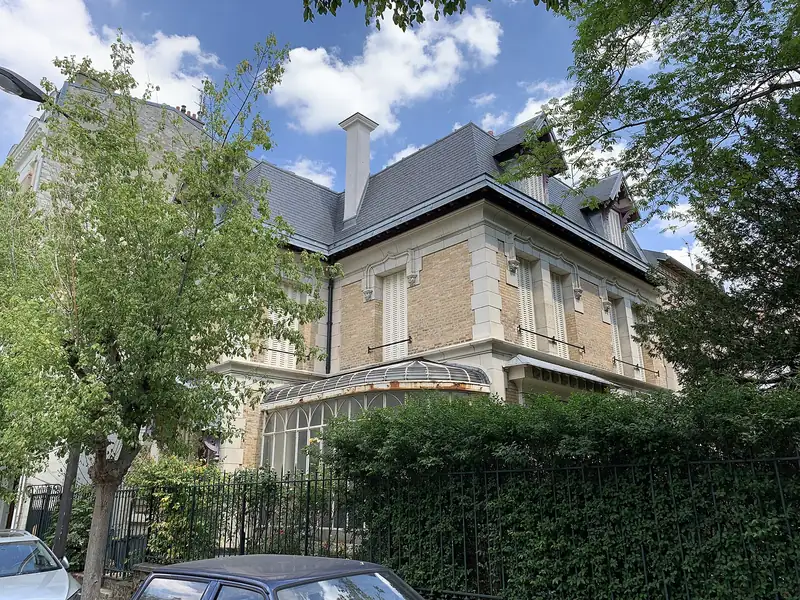 Maison de brique claire derrière les arbres, rue Crébillon à Vincennes