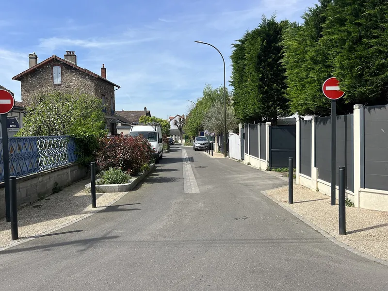 Rue calme d'Argenteuil avec une maison en meulière, des haies et des clôtures de pavillons