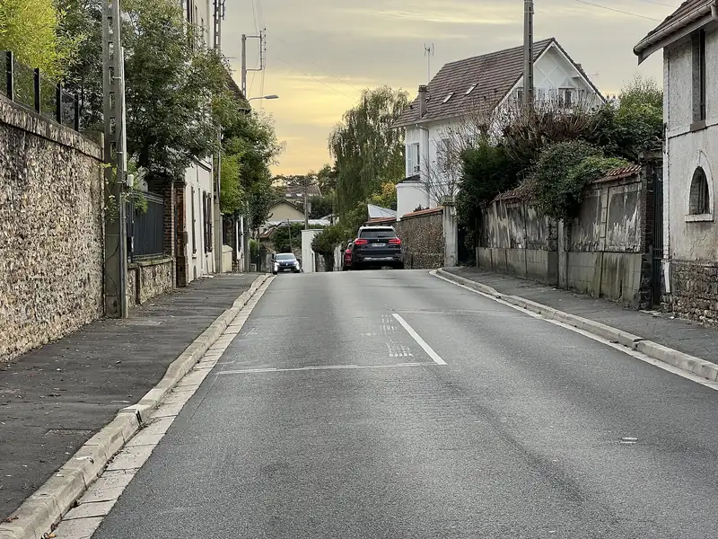 Rue en pente entre des murs de meulière et des maisons à Montmorency