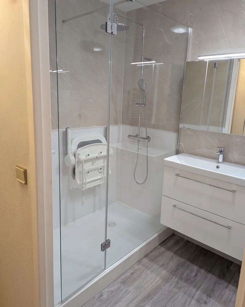 Après&nbsp;: à&nbsp;la&nbsp;place de&nbsp;la&nbsp;baignoire, une douche à&nbsp;paroi vitrée avec un&nbsp;siège rabattable, à&nbsp;côté du&nbsp;meuble vasque