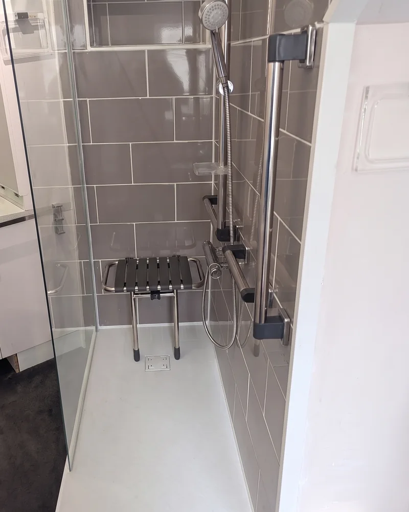 Après&nbsp;: une douche à&nbsp;receveur extra-plat, avec une paroi vitrée, des barres d'appui et&nbsp;un&nbsp;siège