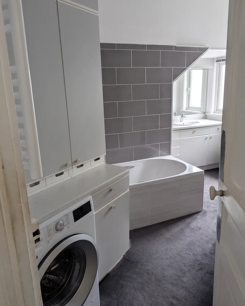 Avant&nbsp;: la&nbsp;salle de&nbsp;bain tout en&nbsp;longueur vue depuis la&nbsp;porte, avec la&nbsp;baignoire derrière le&nbsp;lave-linge