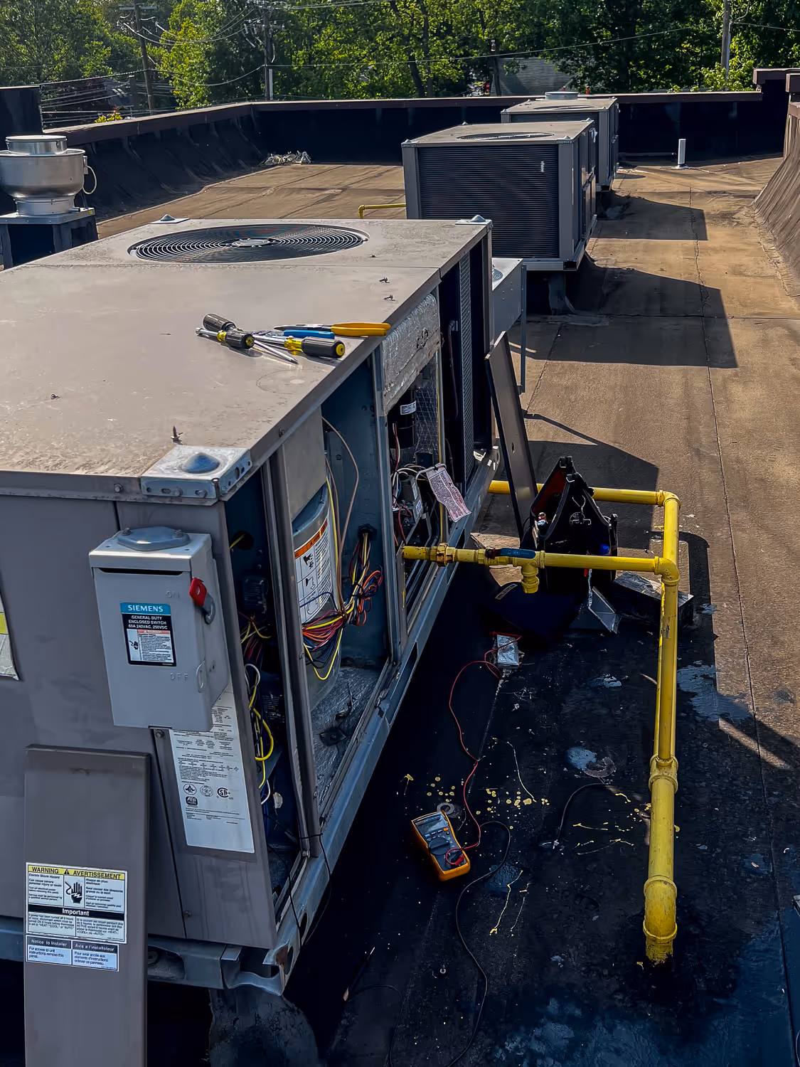 Maintenance tools and equipment placed around a large rooftop air conditioning unit undergoing repair work.