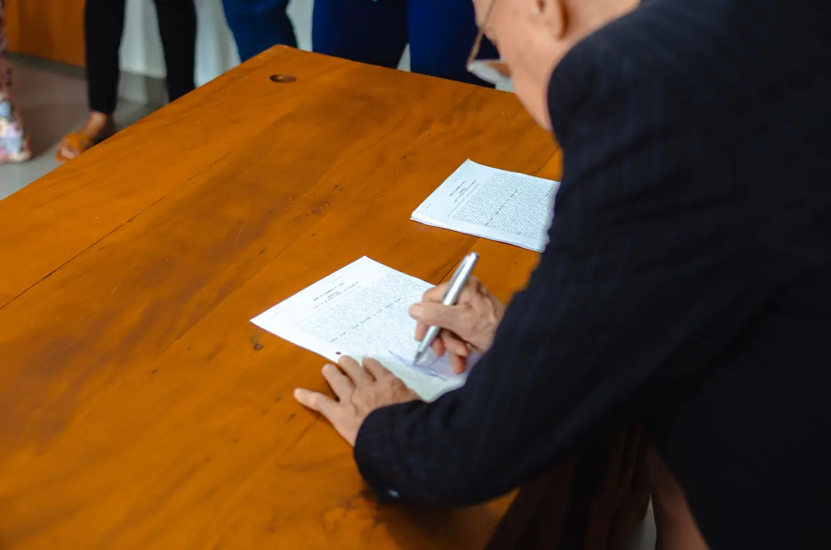 Gros plan d'un homme d'affaires signant des documents officiels à un bureau en bois