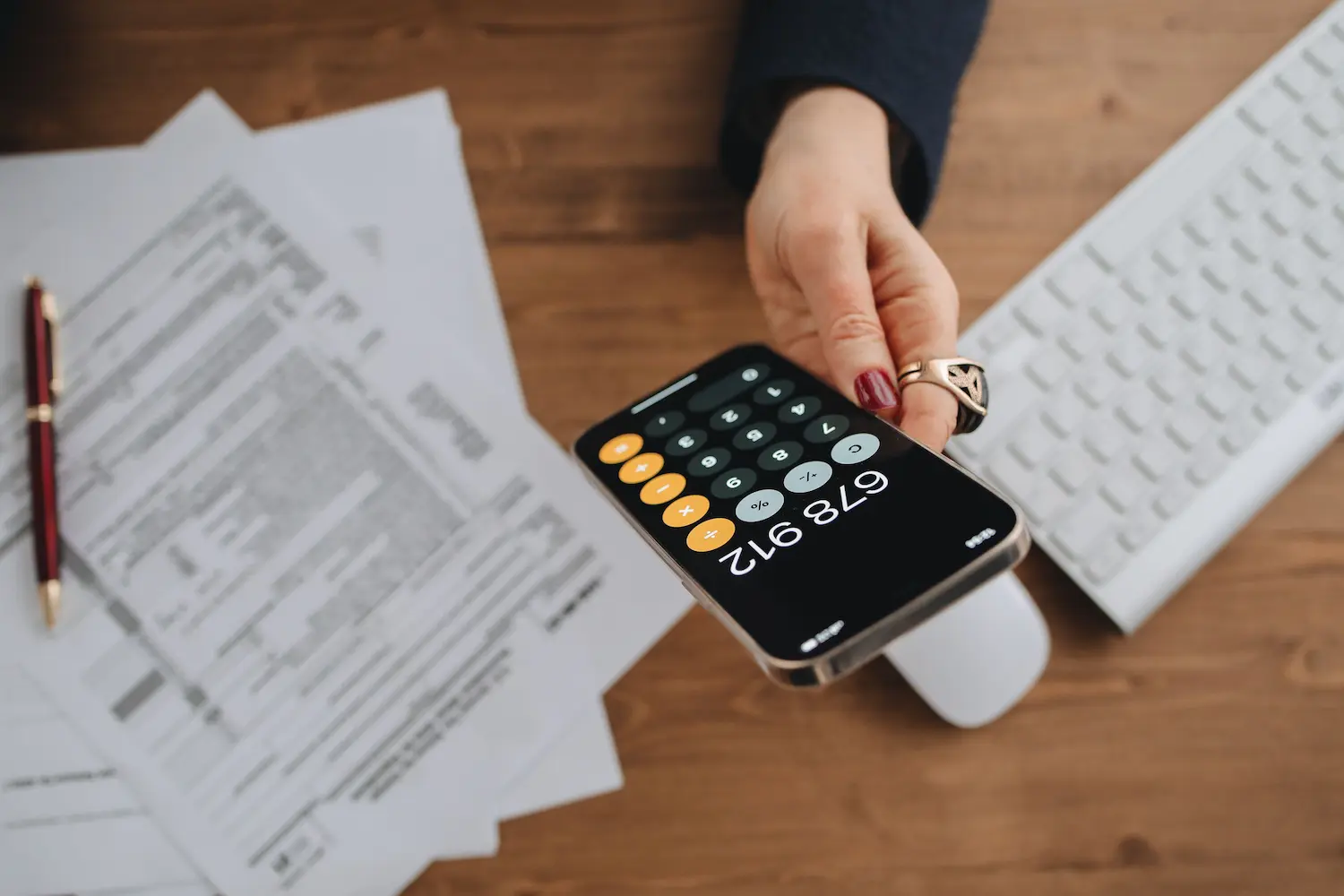 Main tenant une calculatrice smartphone sur des documents fiscaux sur un bureau