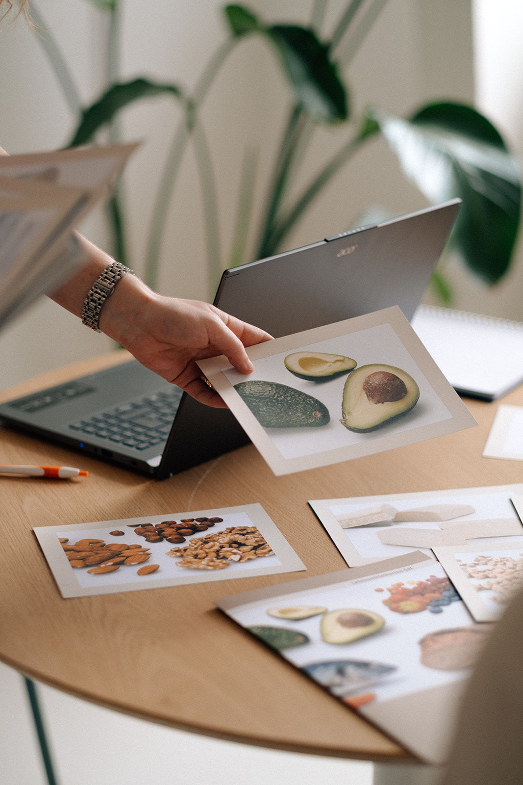 Eine Hand hält eine Karte mit einem Nahrungsmittel in der Hand und zeigt es. Auf dem Tisch unter der Hand befinden sich mehrere Karten mit Nahrungsmitteln.