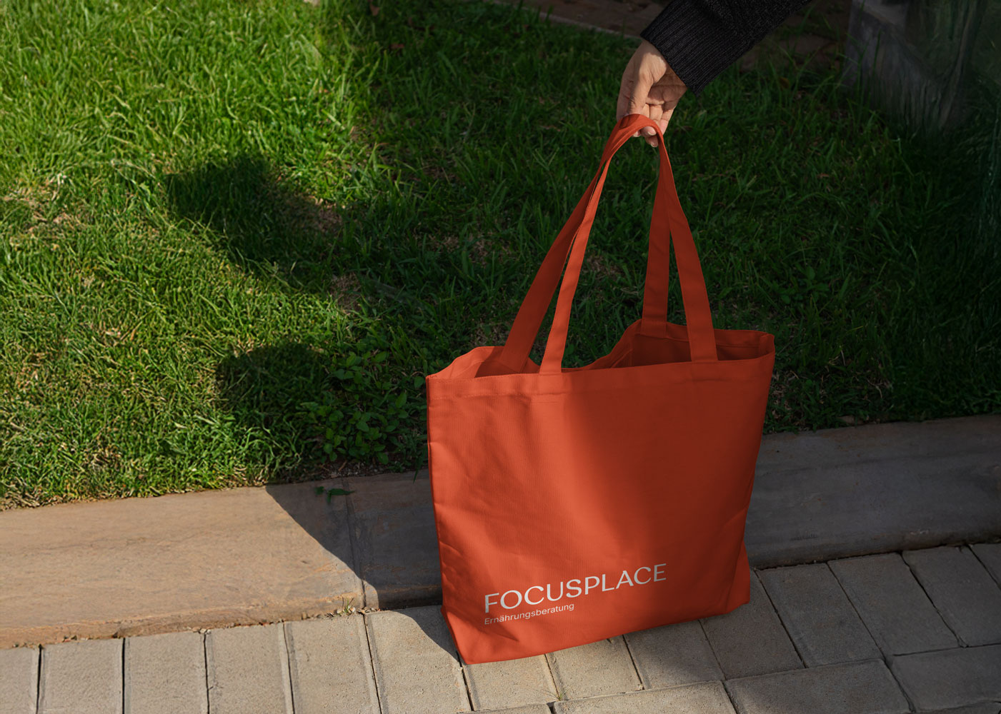 Eine orange Tasche mit dem Logo von FOCUSPLACE drauf.