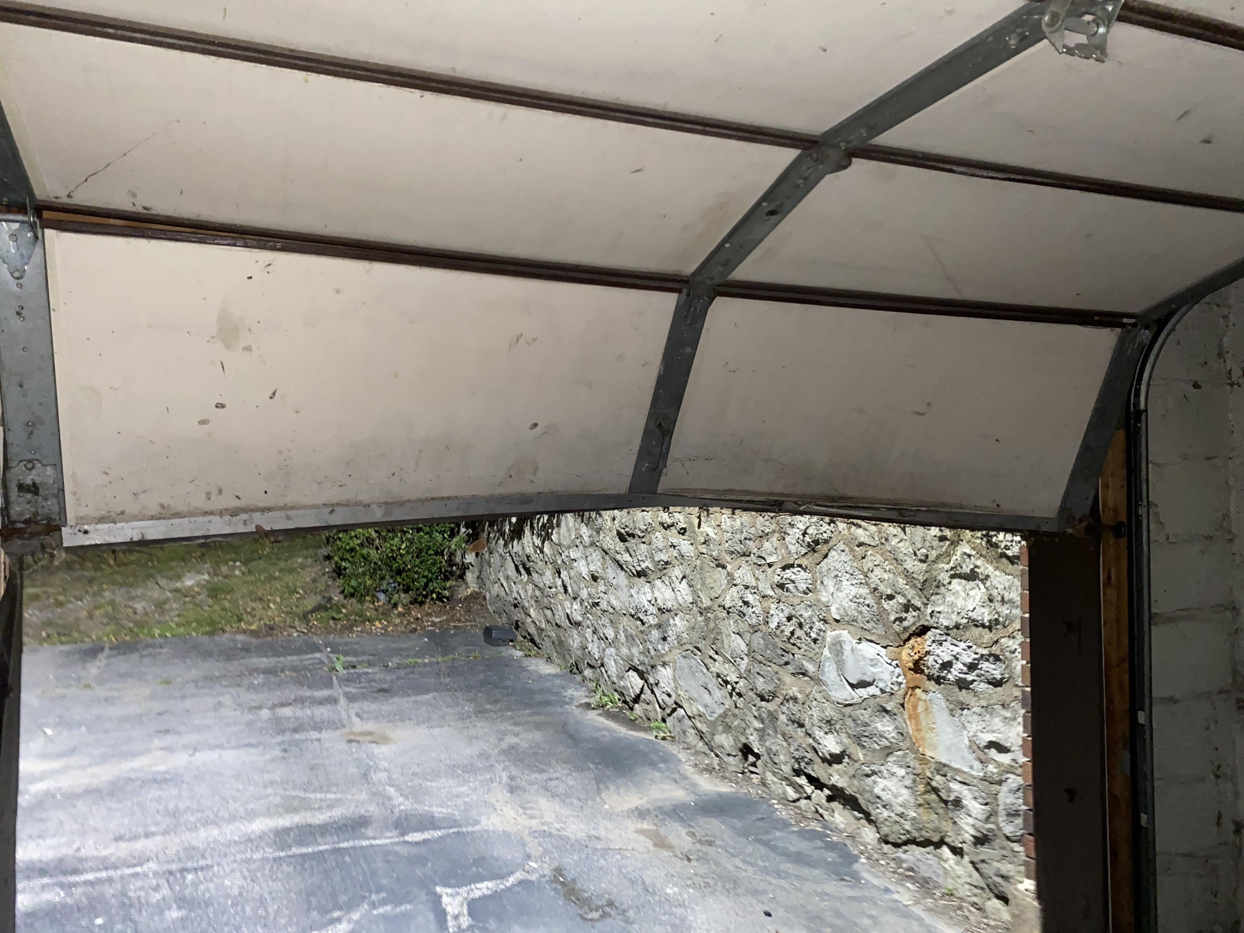 Close-up garage door dent with tool kit on ground