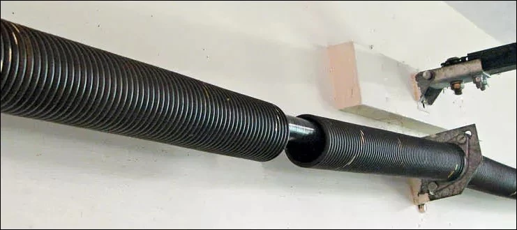 close-up broken garage door spring with toolbox DIY repair risks