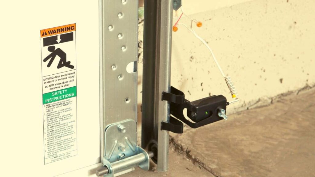 Garage door sensor close-up photo with dust and spiderwebs for maintenance guide