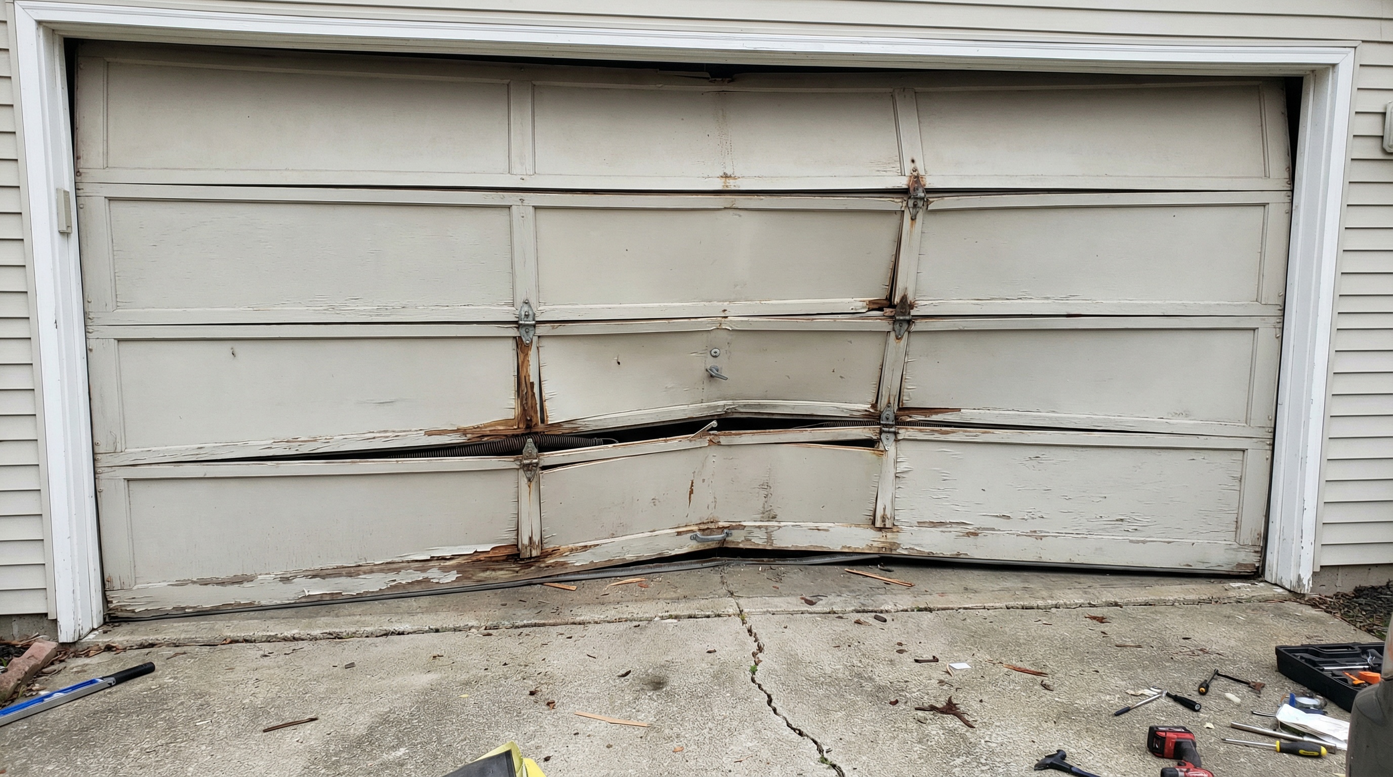 garage door with multiple damaged panels showing extensive warping and structural issues