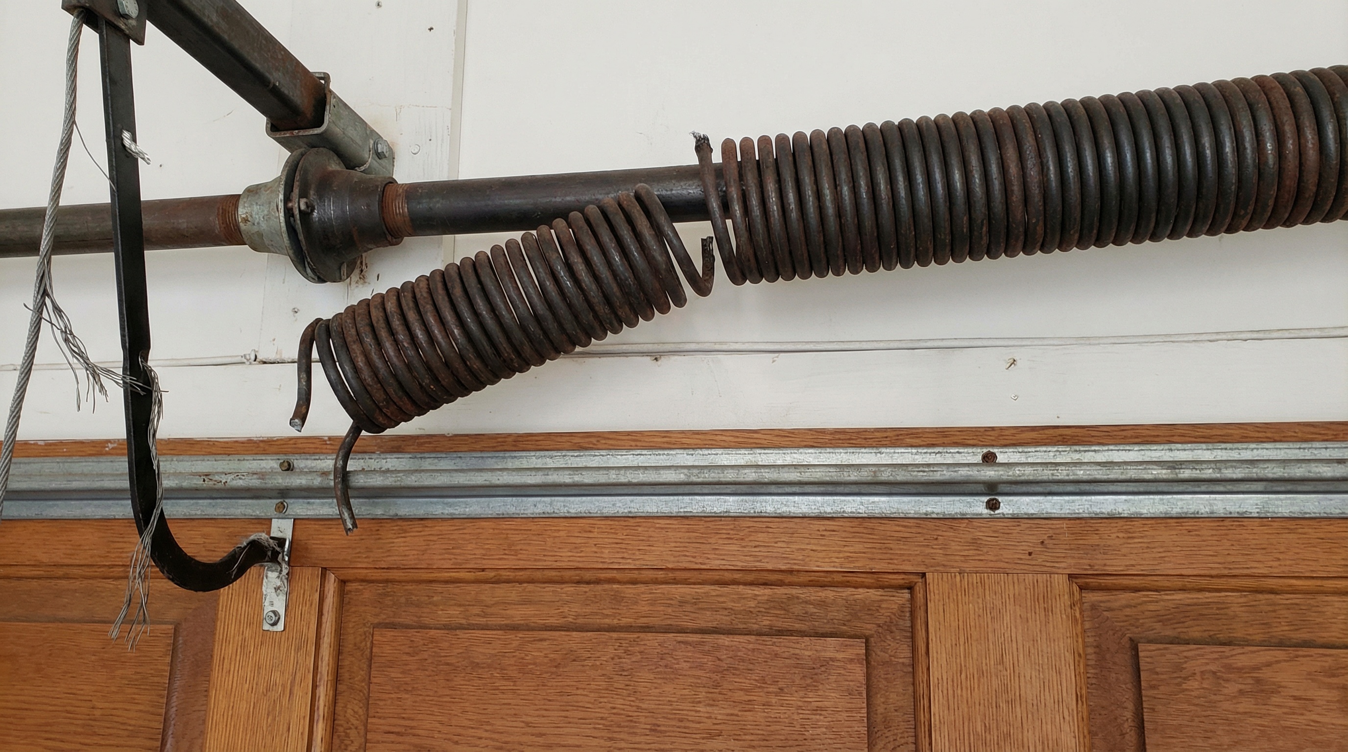 Close-up view of a broken garage door spring showing the gap in the coil
