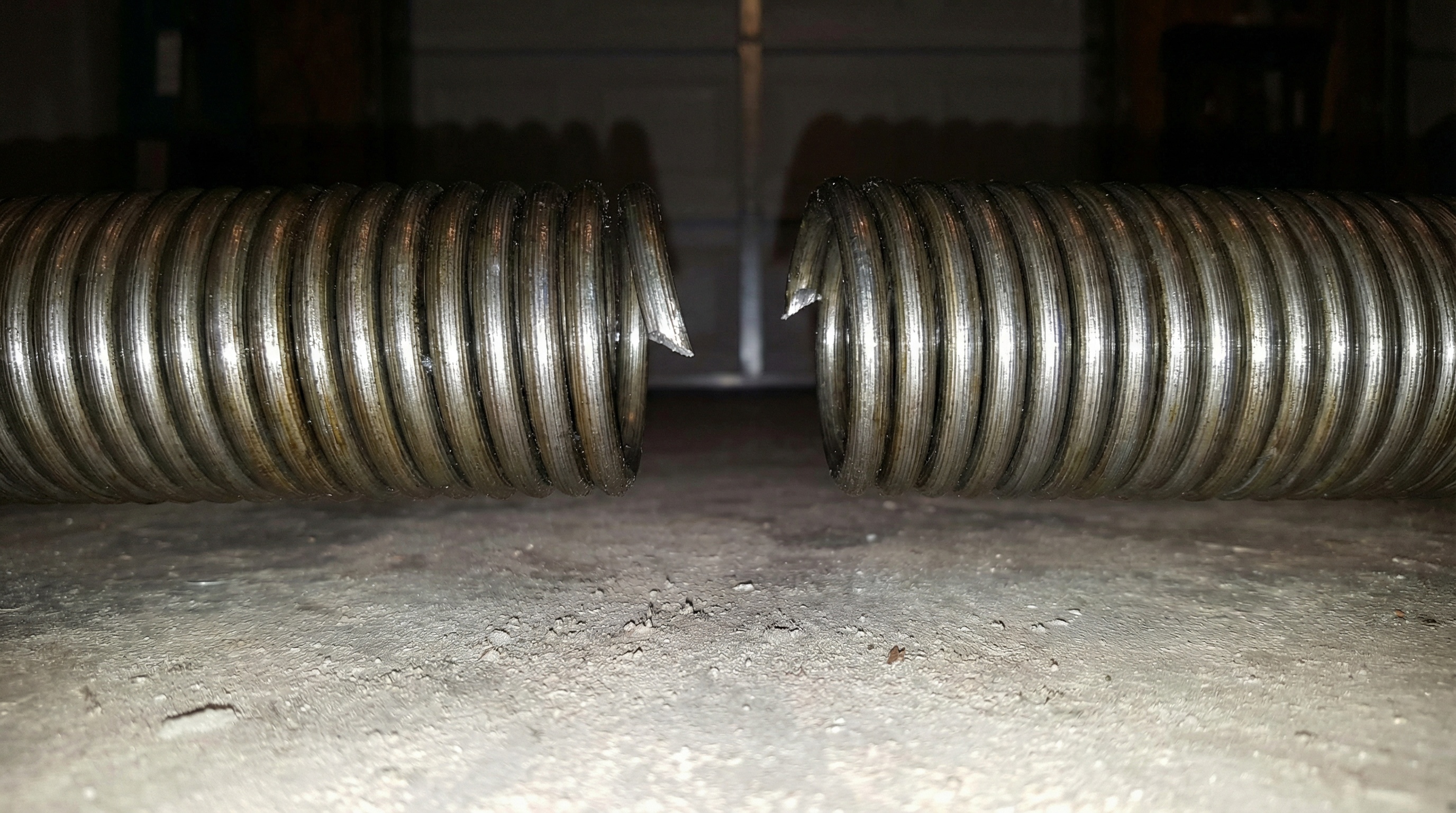 close-up view of broken garage door torsion spring with visible gap