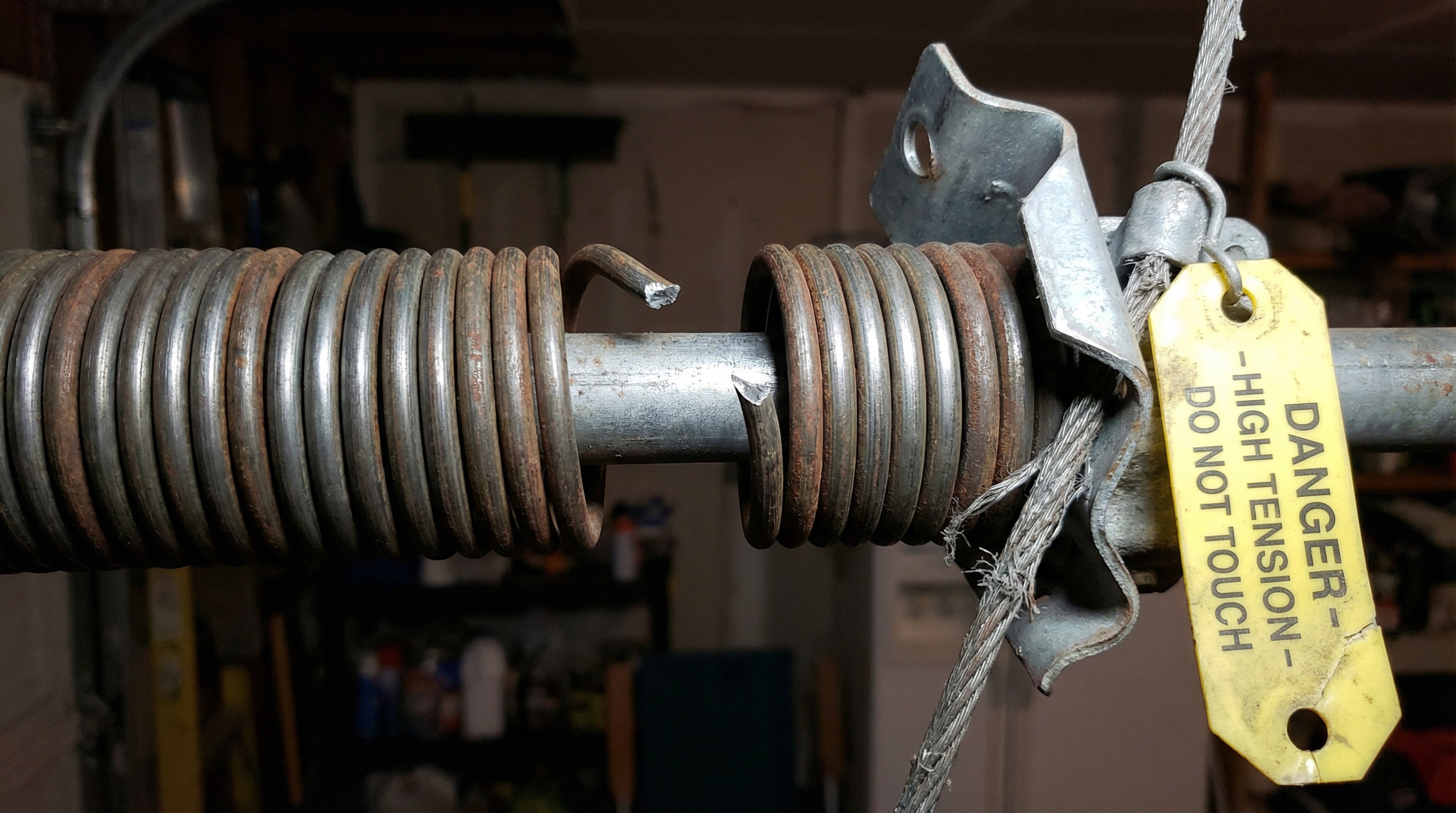 Broken garage door spring showing visible gap in metal coil and damaged mechanism