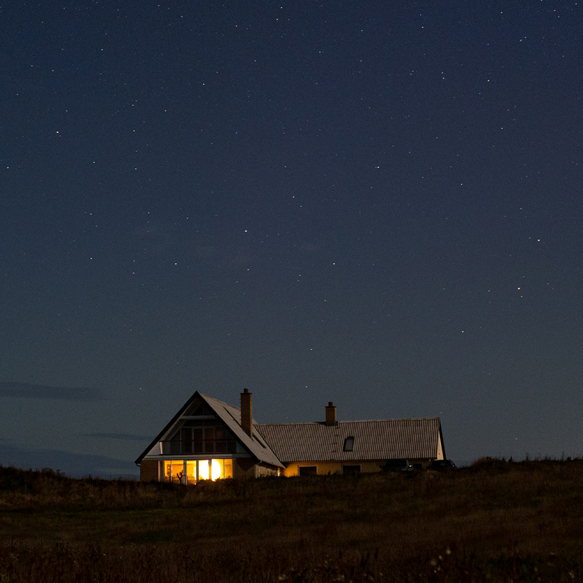Een foto van een huisje op de hei onder een heldere sterrenhemel