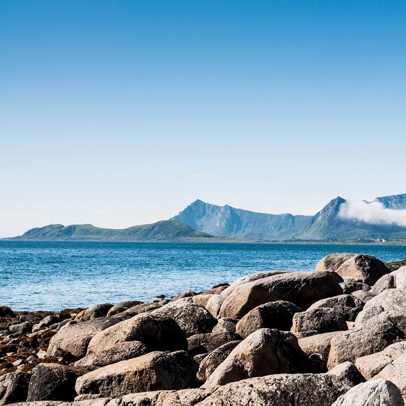 Een foto van de zee met op de achtergrond een aantal bergen