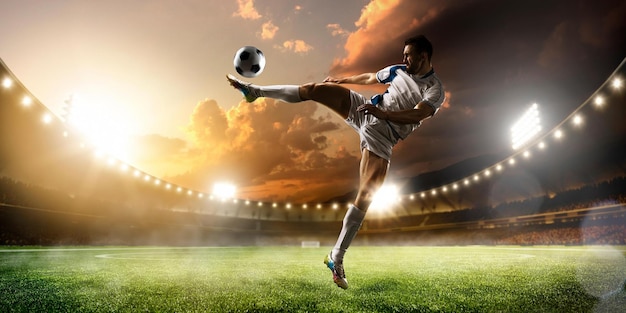 Photo soccer player kicking a ball in a stadium