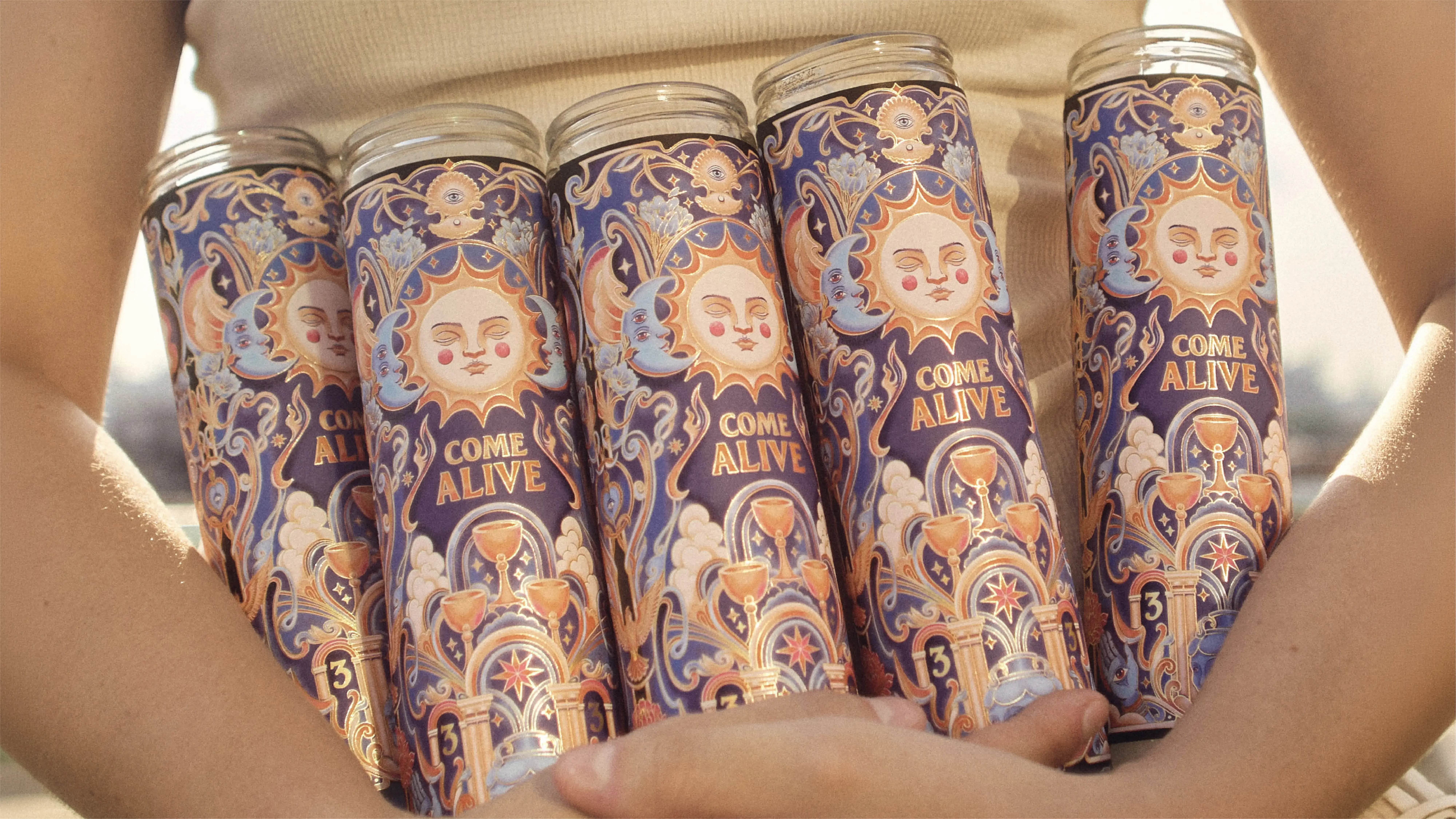 Close-up image of five candles gathered in a person's arms and shining in the evening sun